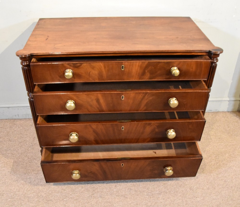 A Regency period mahogany chest of drawers featuring flame mahogany drawer fronts, turned brass knobs, and reeded side columns. View II