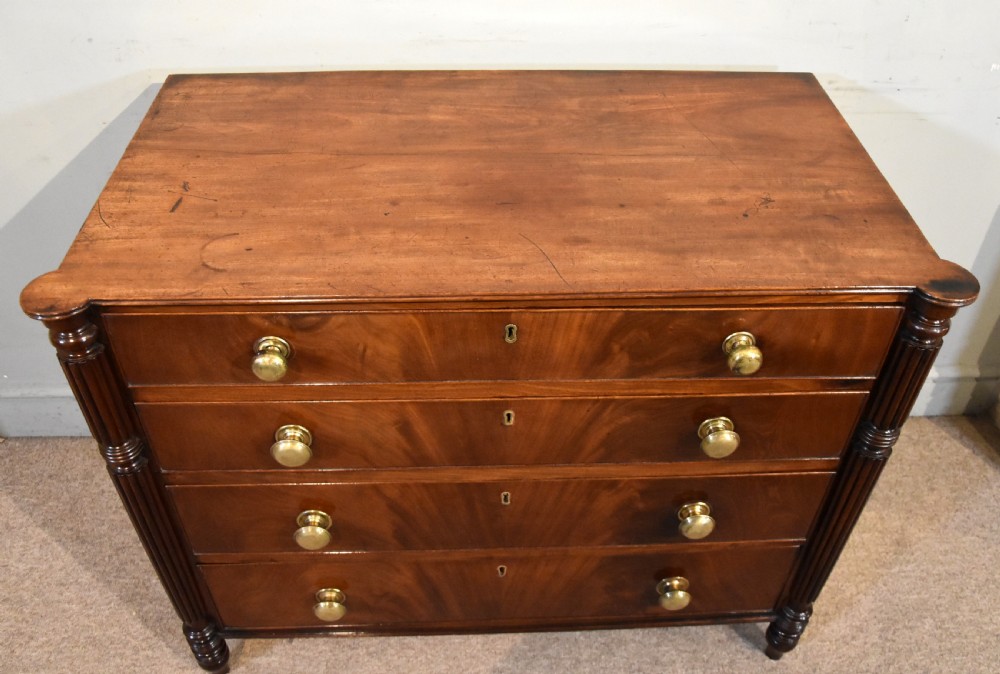A Regency period mahogany chest of drawers featuring flame mahogany drawer fronts, turned brass knobs, and reeded side columns. View III