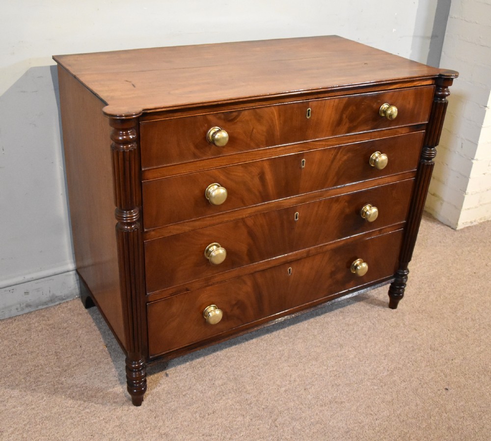 A Regency period mahogany chest of drawers featuring flame mahogany drawer fronts, turned brass knobs, and reeded side columns. View IV