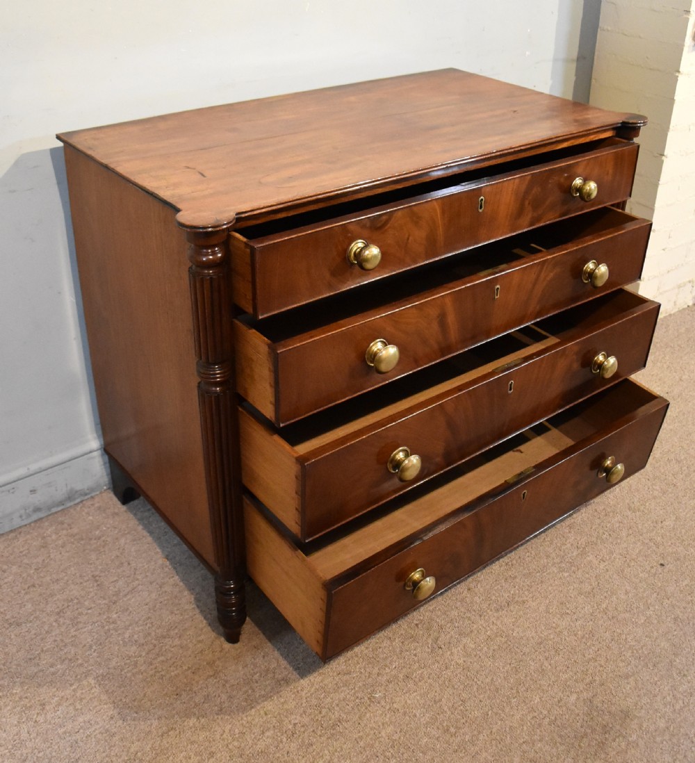 A Regency period mahogany chest of drawers featuring flame mahogany drawer fronts, turned brass knobs, and reeded side columns. View V