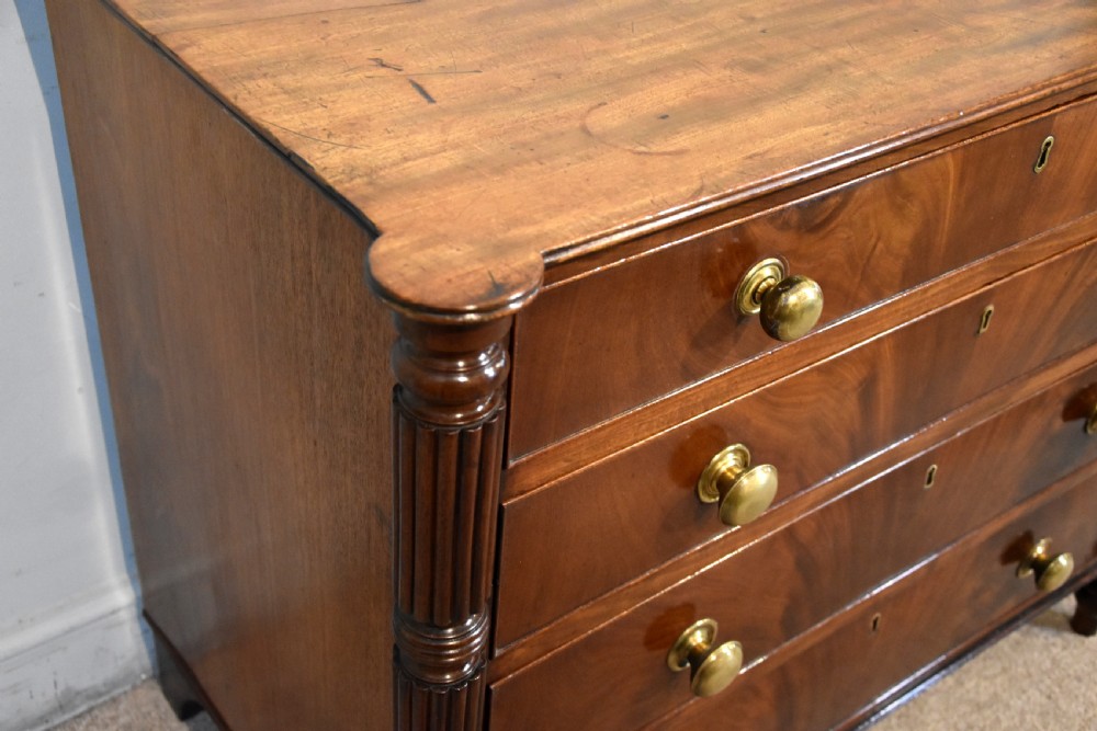 A Regency period mahogany chest of drawers featuring flame mahogany drawer fronts, turned brass knobs, and reeded side columns. View VI