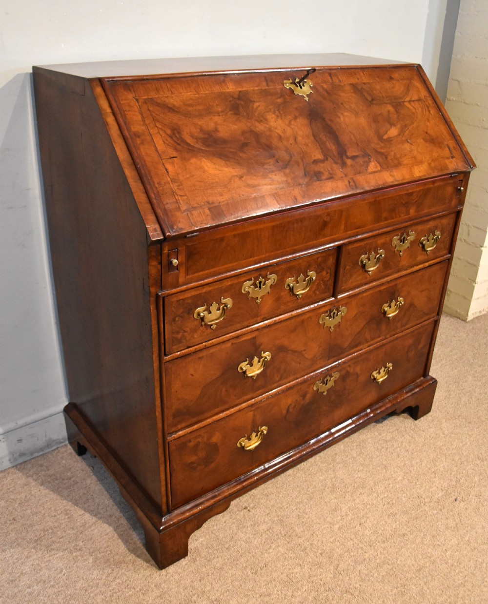 A George II walnut veneered bureau featuring a slant-front writing lid above four drawers with decorative brass handles and bracket feet. View VII