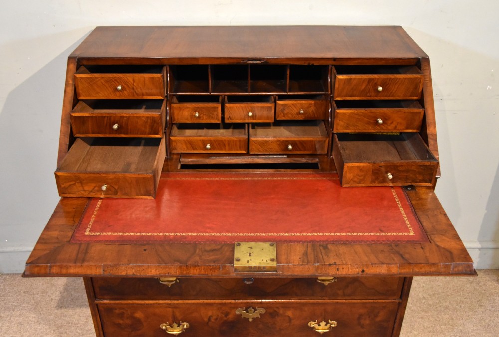 A George II walnut veneered bureau featuring a slant-front writing lid above four drawers with decorative brass handles and bracket feet. View VIII