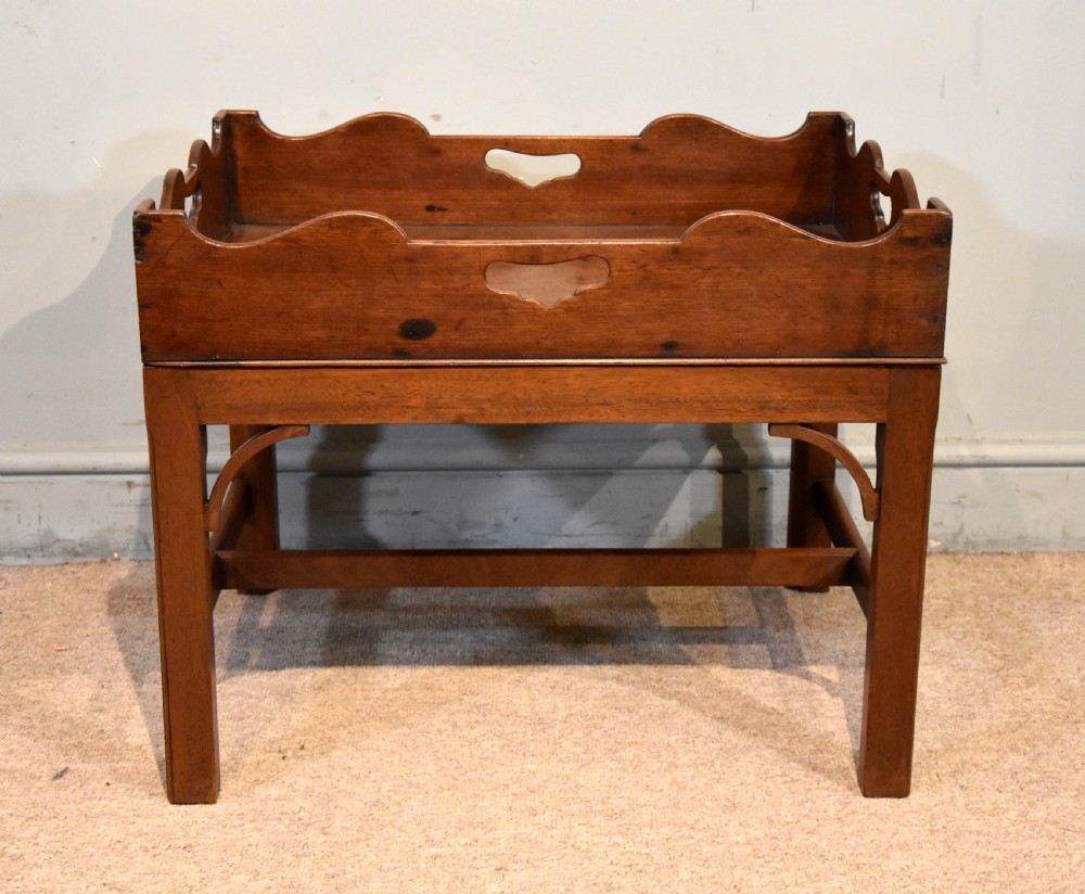A mid-eighteenth-century mahogany butlers tray featuring scalloped gallery sides with cut-out handles, resting on a fitted rectangular wooden stand with corner spandrels. View II