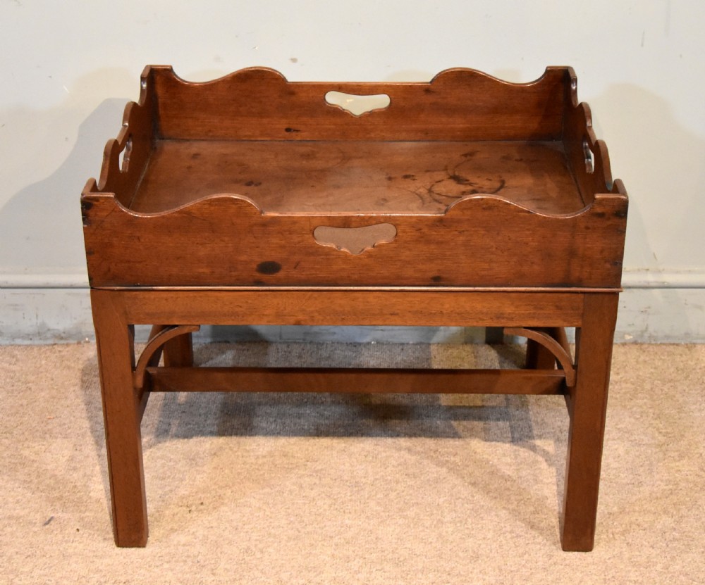 A mid-eighteenth-century mahogany butlers tray featuring scalloped gallery sides with cut-out handles, resting on a fitted rectangular wooden stand with corner spandrels. View III