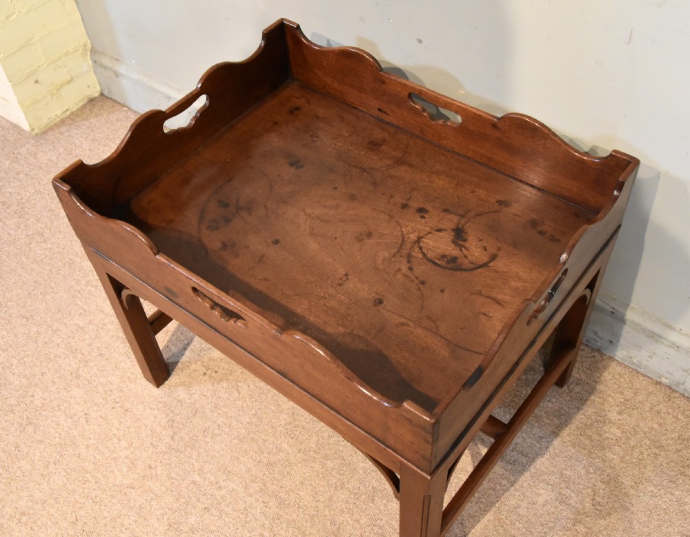 A mid-eighteenth-century mahogany butlers tray featuring scalloped gallery sides with cut-out handles, resting on a fitted rectangular wooden stand with corner spandrels. View IV