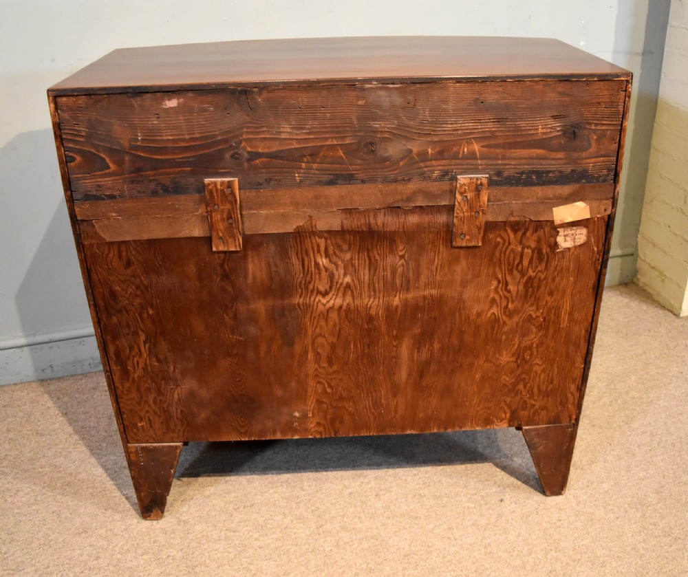 A Regency period mahogany bow-fronted chest featuring three full-width drawers with brass handles and splayed bracket feet. View VIII