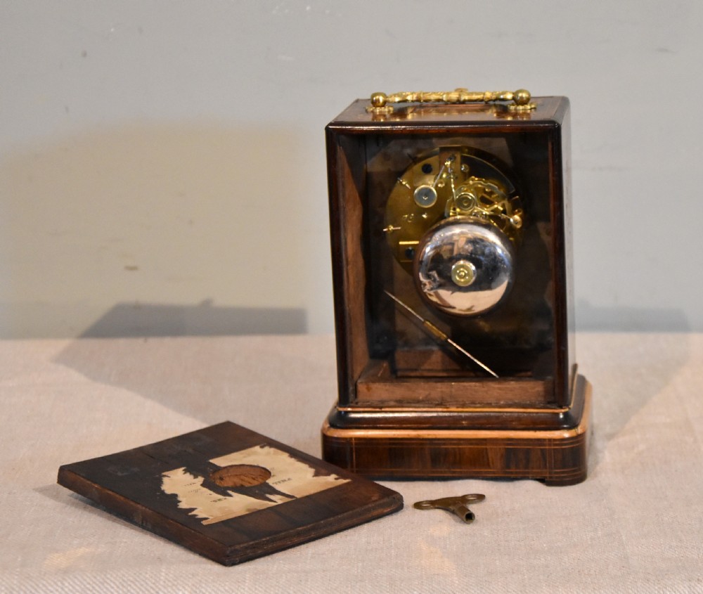An antique French rectangular rosewood mantel clock featuring foliate marquetry inlay, a silvered engine-turned dial with Roman numerals, and a gilt brass handle. View IV