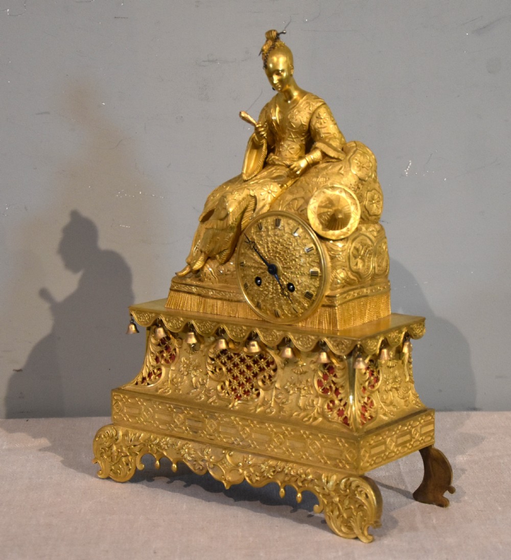 An antique French ormolu mantel clock featuring a sculpted Chinoiserie figure seated atop an intricate tiered base with suspended bells. View III