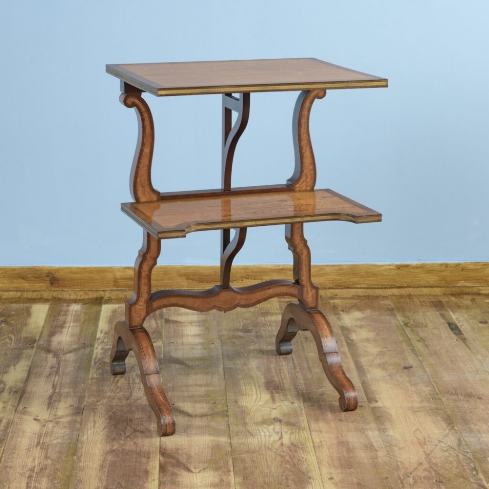 A 19th-century French satinwood folding tea table featuring two tiers, scroll-shaped uprights, crossbanded borders, and splayed trestle legs.