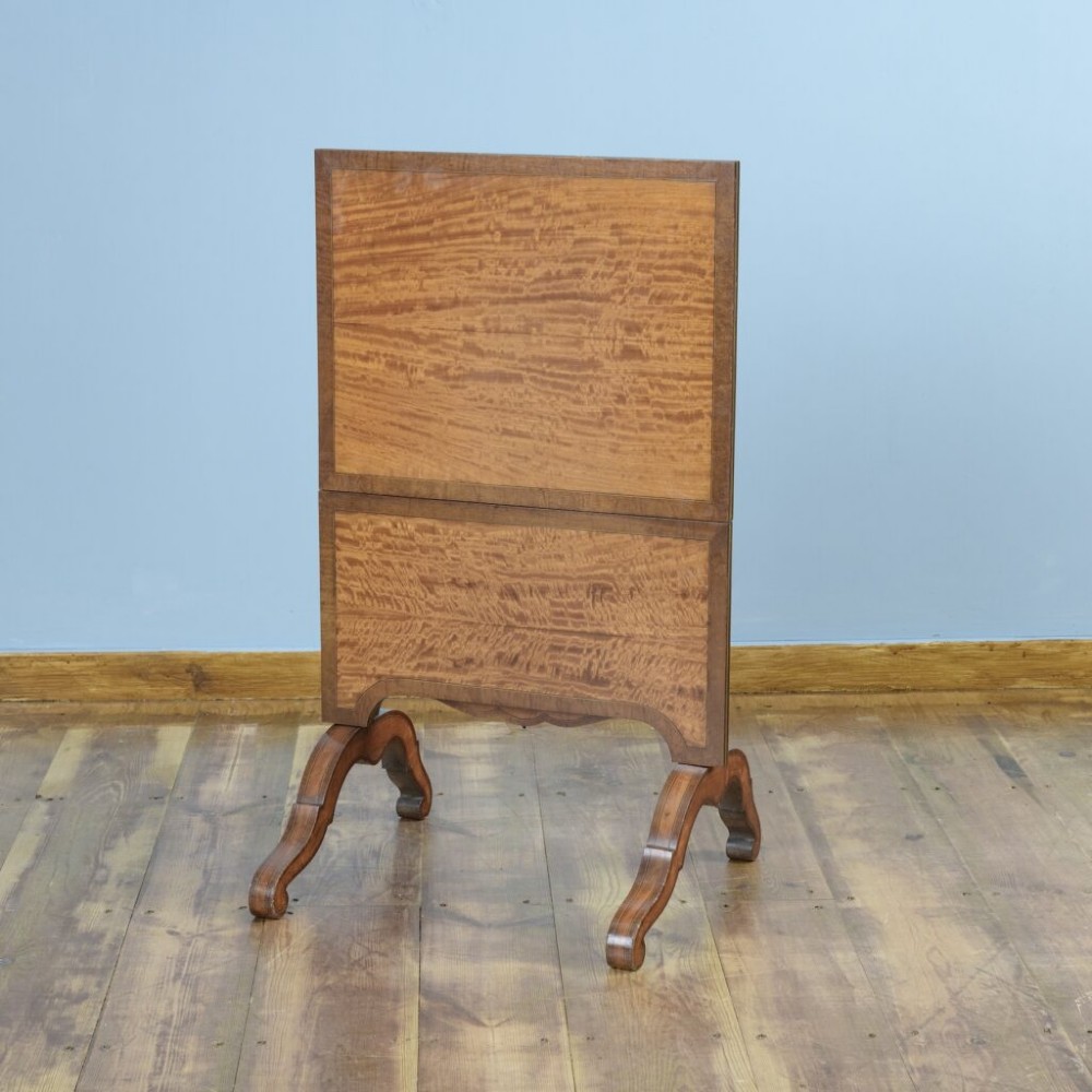 A 19th-century French satinwood folding tea table featuring two tiers, scroll-shaped uprights, crossbanded borders, and splayed trestle legs. View II