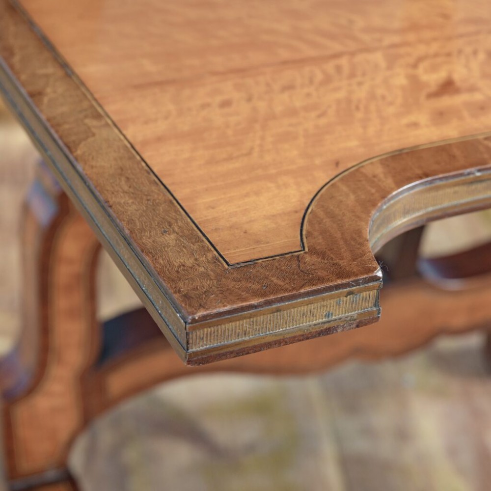 A 19th-century French satinwood folding tea table featuring two tiers, scroll-shaped uprights, crossbanded borders, and splayed trestle legs. View III