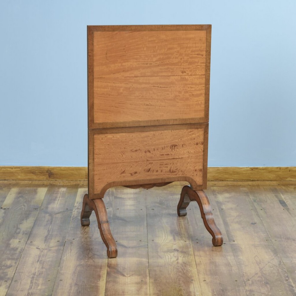 A 19th-century French satinwood folding tea table featuring two tiers, scroll-shaped uprights, crossbanded borders, and splayed trestle legs. View V