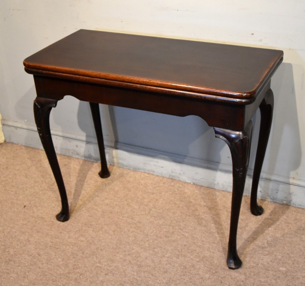 A dark mahogany George III fold-over card table resting on four slender carved cabriole legs with pad feet. View II
