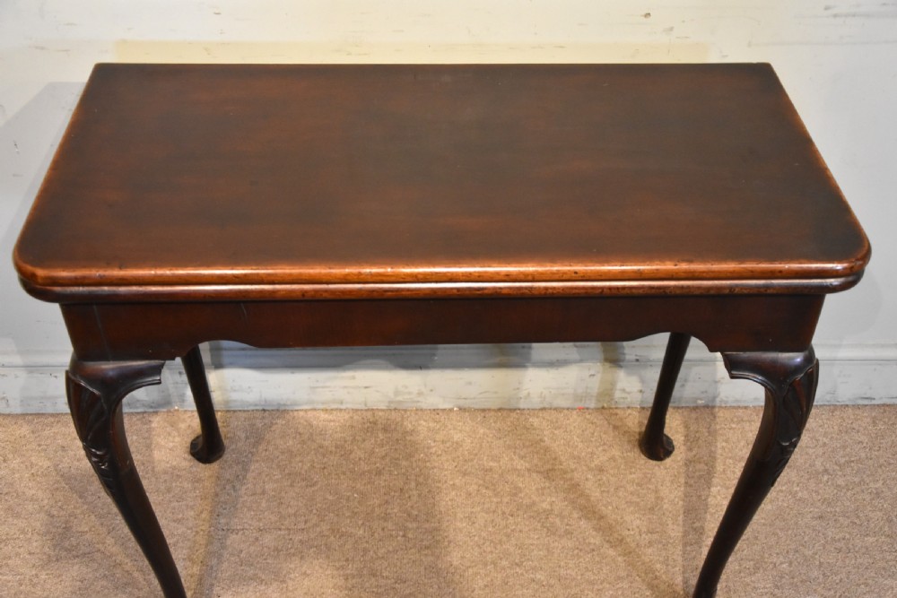 A dark mahogany George III fold-over card table resting on four slender carved cabriole legs with pad feet. View III