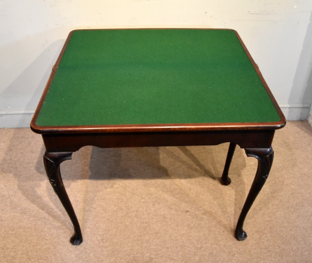 A dark mahogany George III fold-over card table resting on four slender carved cabriole legs with pad feet. View V