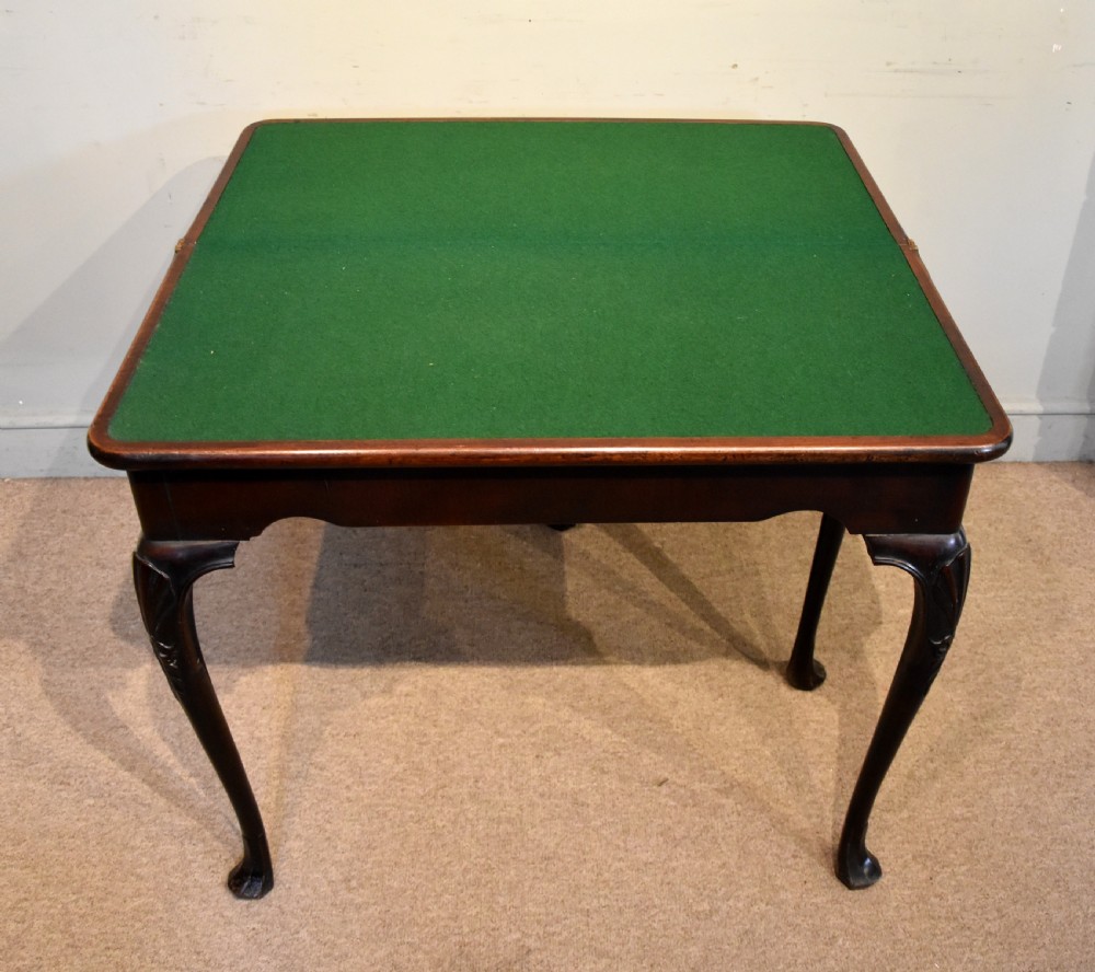 A dark mahogany George III fold-over card table resting on four slender carved cabriole legs with pad feet. View VI