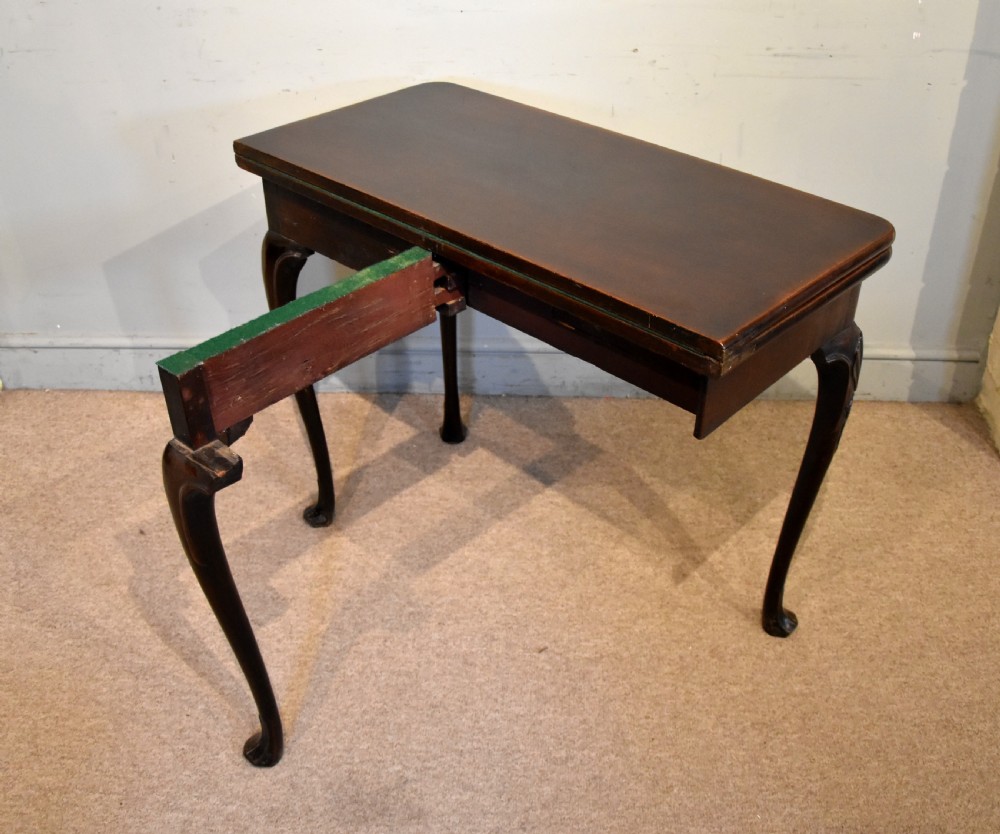 A dark mahogany George III fold-over card table resting on four slender carved cabriole legs with pad feet. View VII