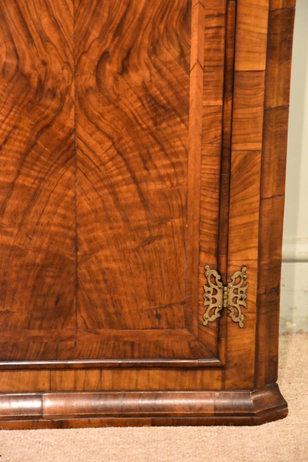 A George I walnut corner cupboard featuring a tiered open shelf superstructure above a panelled door with book-matched veneer and brass hinges. View VII