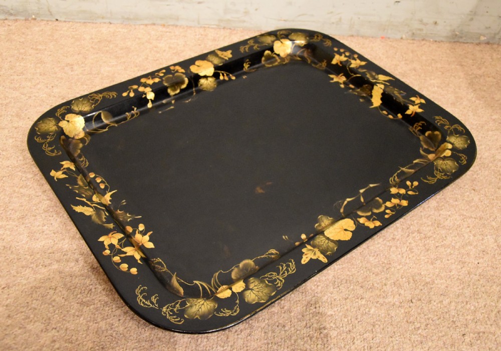 A large rectangular black lacquered Regency papier-mache tray decorated with gilt foliage along its raised rim. View II