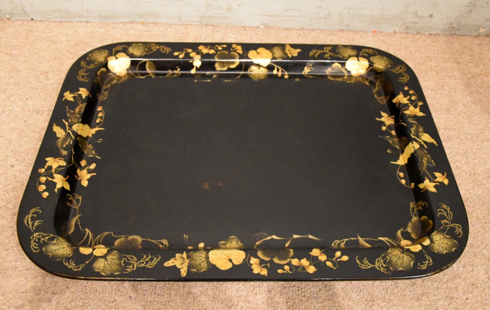 A large rectangular black lacquered Regency papier-mache tray decorated with gilt foliage along its raised rim. View III