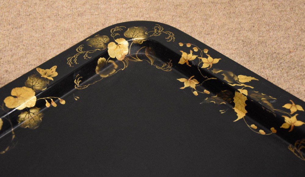 A large rectangular black lacquered Regency papier-mache tray decorated with gilt foliage along its raised rim. View IV