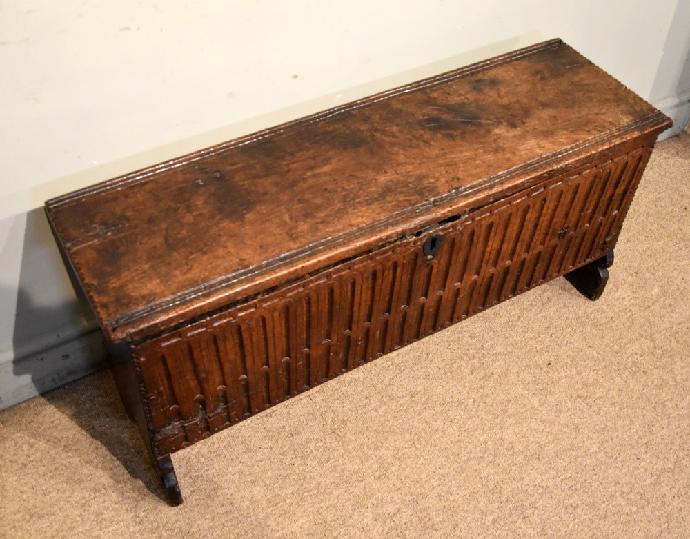 A sixteenth-century dark oak coffer featuring vertical fluted carvings across the front panel and a metal keyhole escutcheon. View V