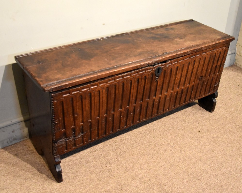 A sixteenth-century dark oak coffer featuring vertical fluted carvings across the front panel and a metal keyhole escutcheon. View VI