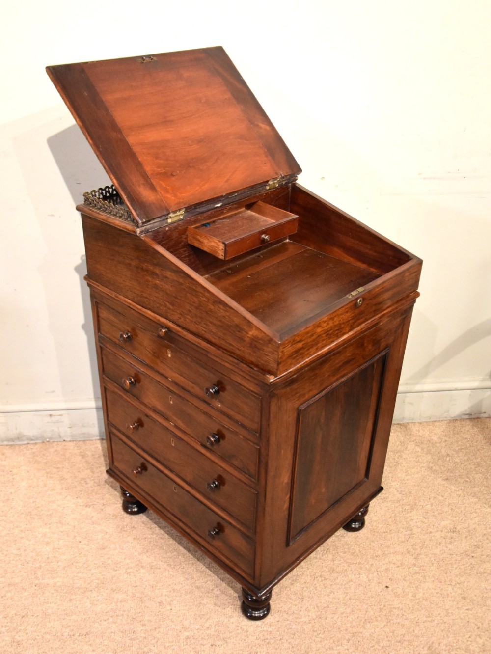 A Regency rosewood Davenport desk featuring a slanted green leather writing slope, a brass gallery rail, and four side drawers with turned wooden knobs. View II