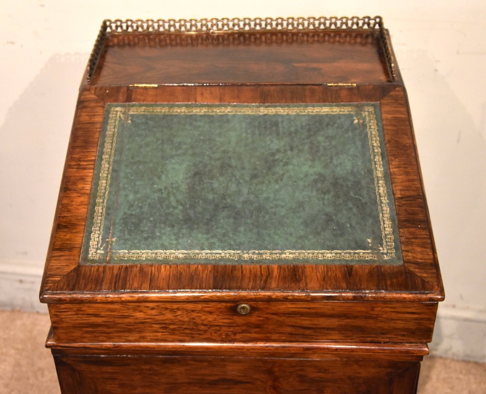 A Regency rosewood Davenport desk featuring a slanted green leather writing slope, a brass gallery rail, and four side drawers with turned wooden knobs. View IV