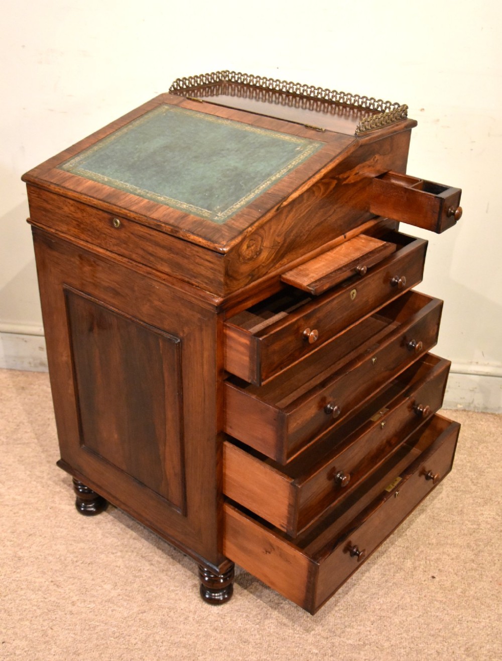 A Regency rosewood Davenport desk featuring a slanted green leather writing slope, a brass gallery rail, and four side drawers with turned wooden knobs. View V