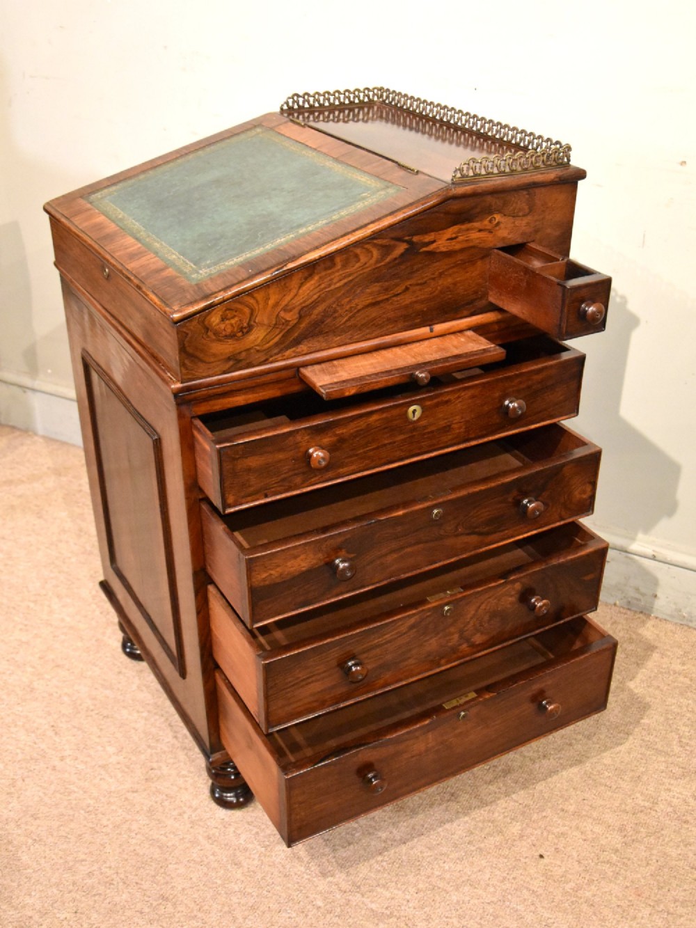 A Regency rosewood Davenport desk featuring a slanted green leather writing slope, a brass gallery rail, and four side drawers with turned wooden knobs. View VI