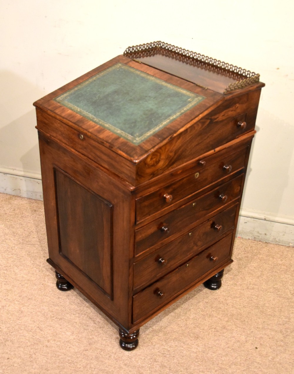A Regency rosewood Davenport desk featuring a slanted green leather writing slope, a brass gallery rail, and four side drawers with turned wooden knobs. View VII