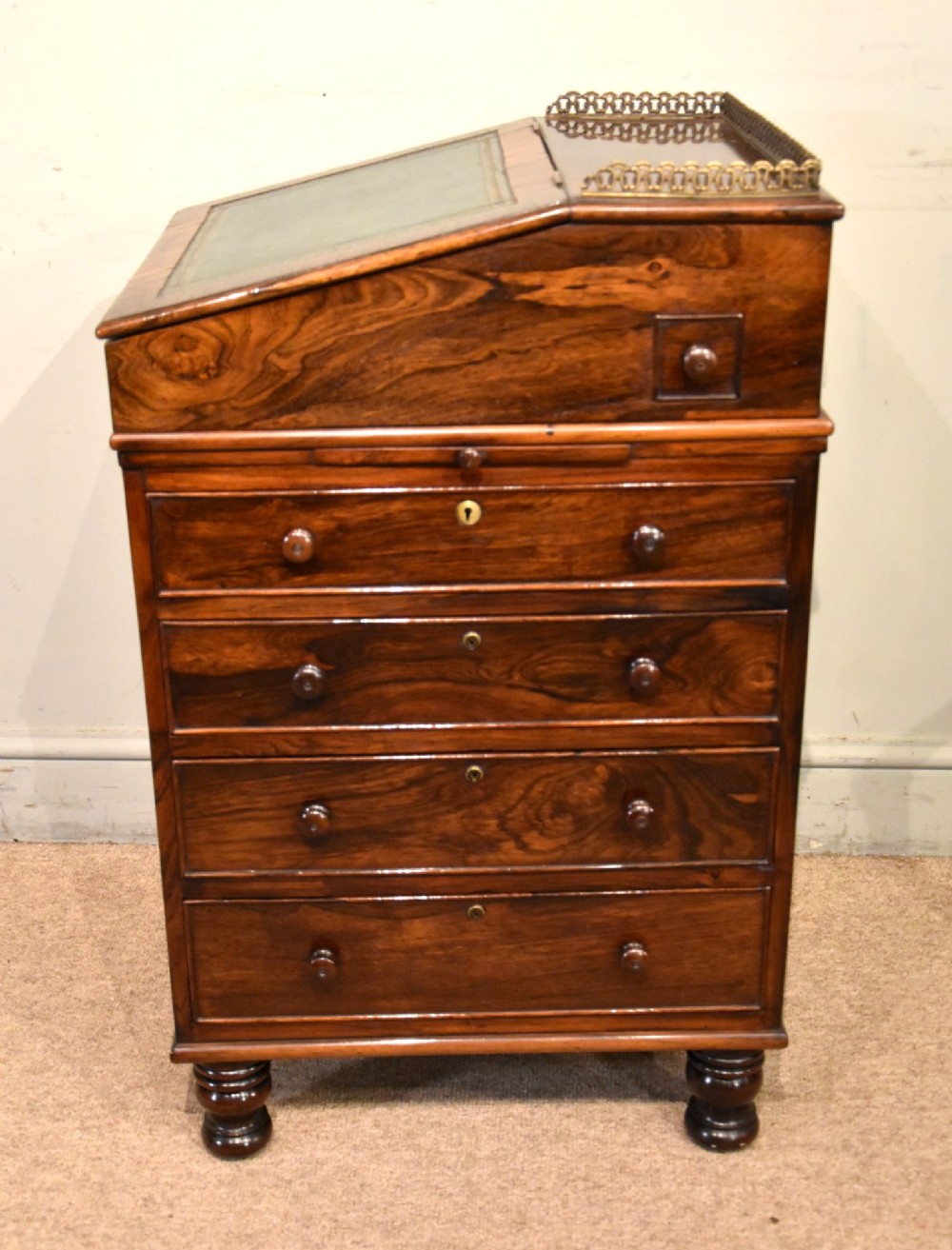 A Regency rosewood Davenport desk featuring a slanted green leather writing slope, a brass gallery rail, and four side drawers with turned wooden knobs. View VIII