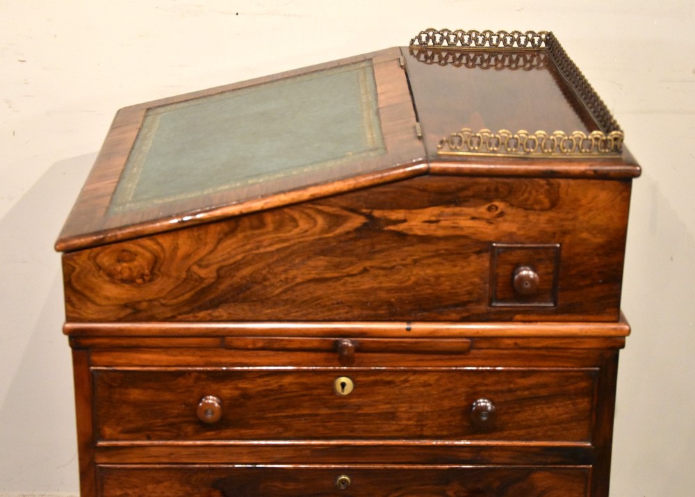 A Regency rosewood Davenport desk featuring a slanted green leather writing slope, a brass gallery rail, and four side drawers with turned wooden knobs. View IX