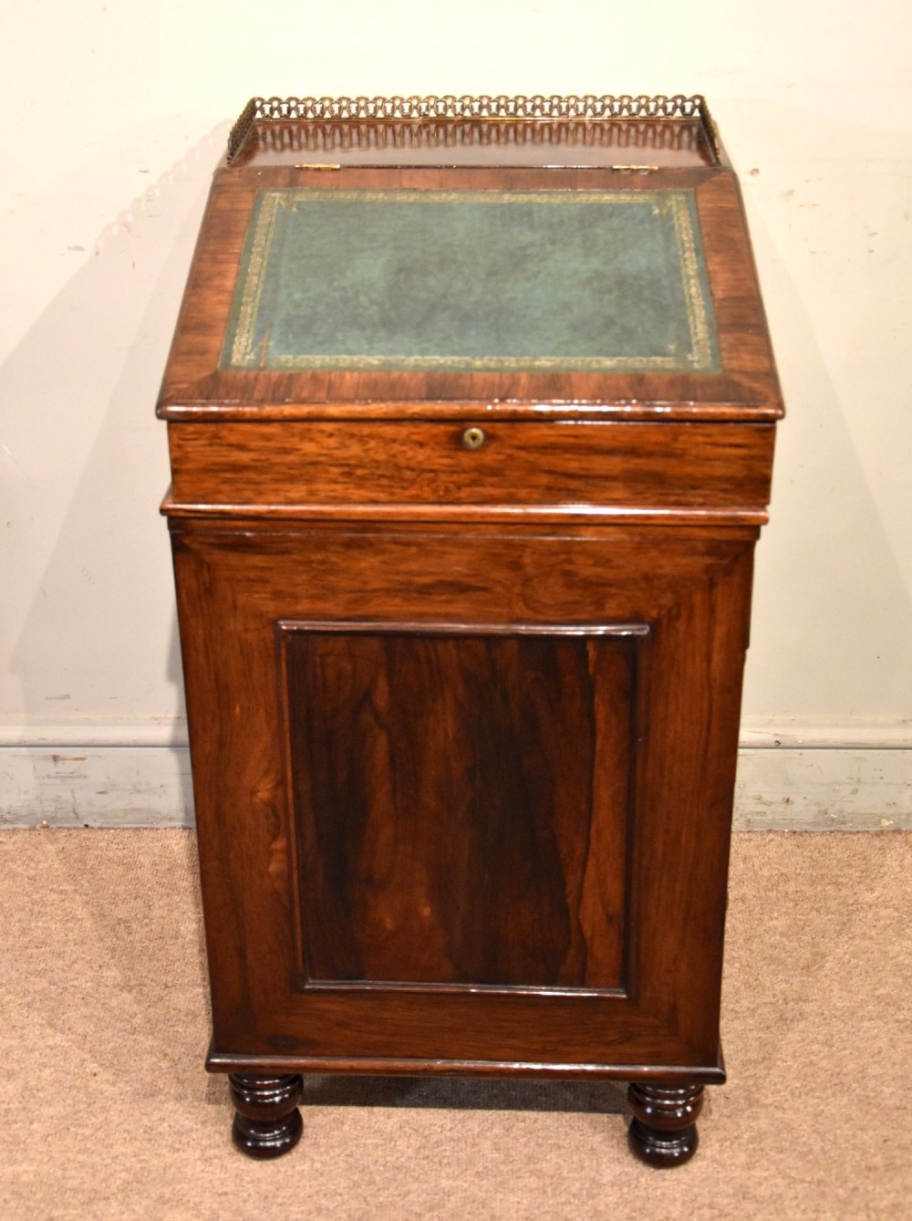 A Regency rosewood Davenport desk featuring a slanted green leather writing slope, a brass gallery rail, and four side drawers with turned wooden knobs. View X