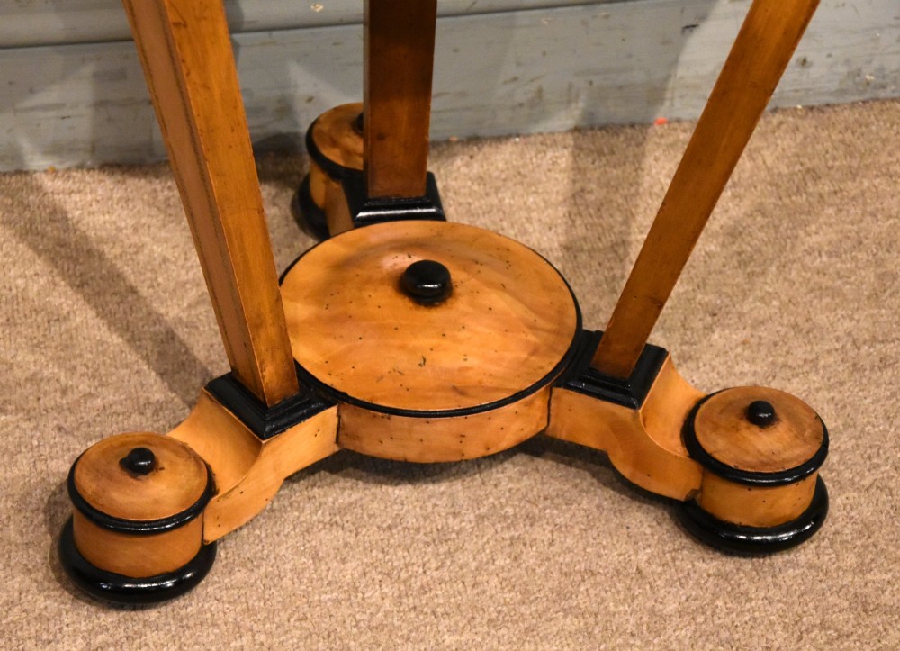 A circular Biedermeier centre table featuring a painted classical top panel, golden birch veneer apron with key, ebonised trim, and a tripod base. View IV