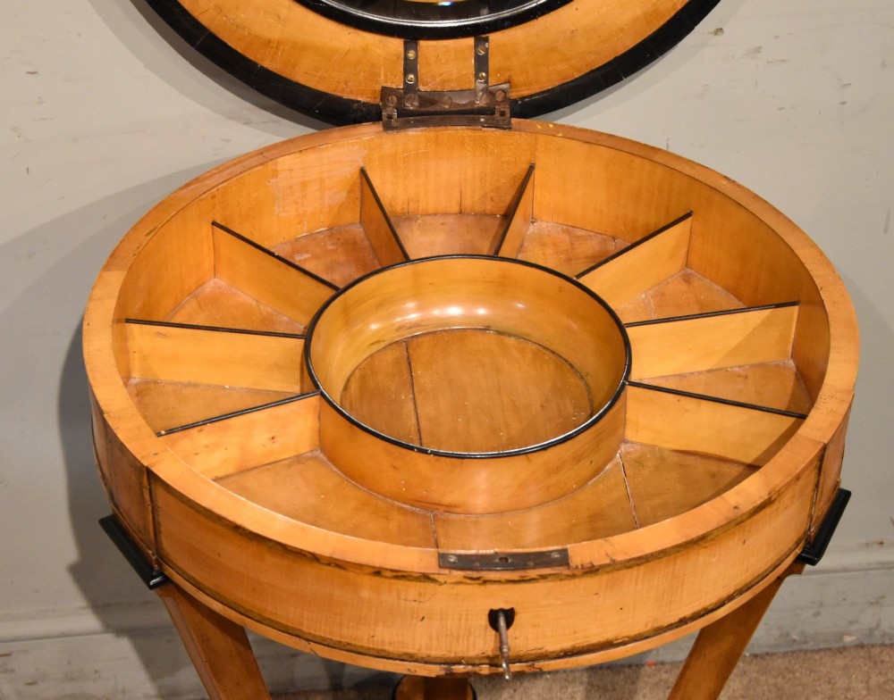 A circular Biedermeier centre table featuring a painted classical top panel, golden birch veneer apron with key, ebonised trim, and a tripod base. View V