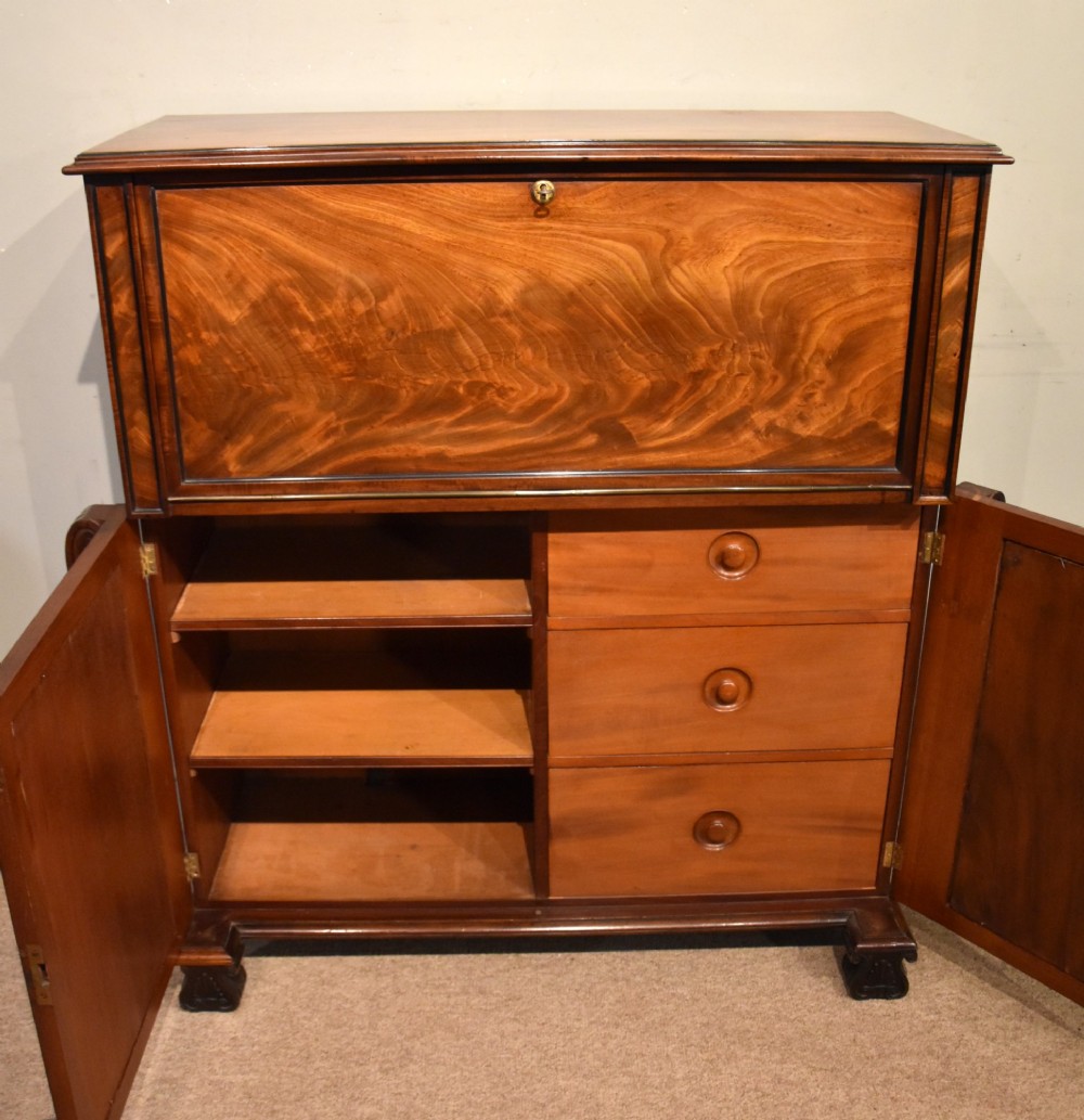 A Regency flame mahogany secretaire cabinet featuring a drop-front writing compartment above two doors with brass trellis grilles and carved pilasters. View III