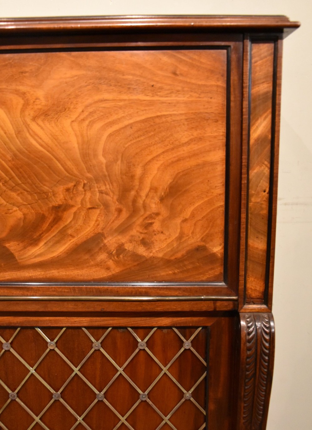 A Regency flame mahogany secretaire cabinet featuring a drop-front writing compartment above two doors with brass trellis grilles and carved pilasters. View VII