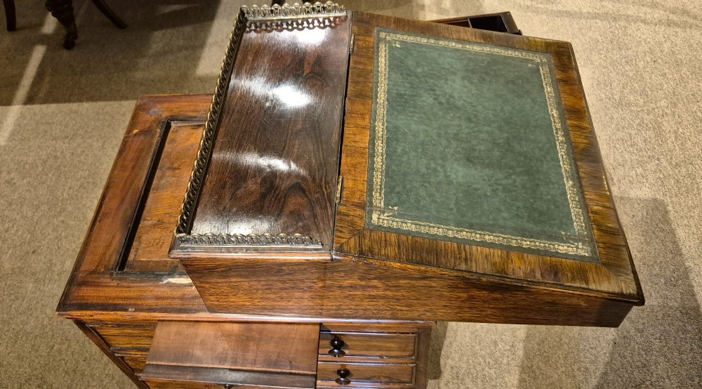 A Regency rosewood Davenport desk featuring a slanted green leather writing slope, a brass gallery rail, and four side drawers with turned wooden knobs. View XI