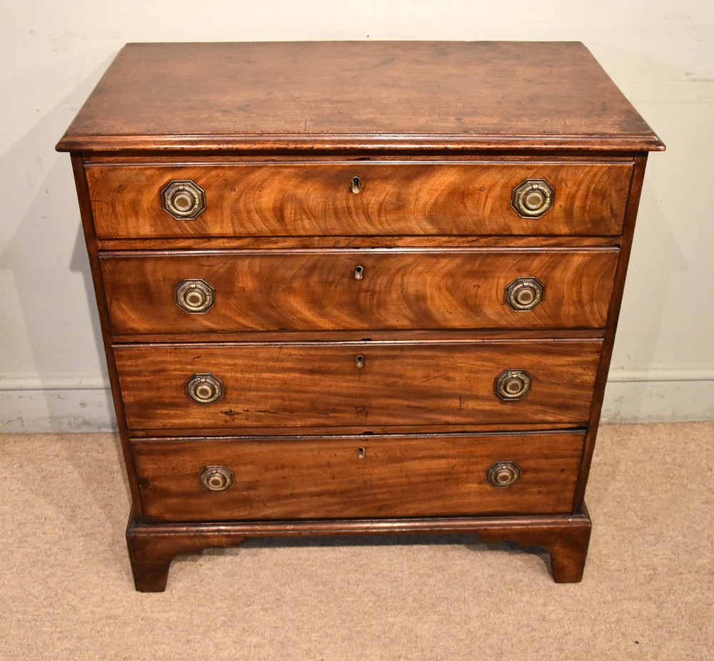 An 18th-century George III mahogany chest featuring four graduated drawers with flame mahogany veneer, octagonal brass handles, and bracket feet.