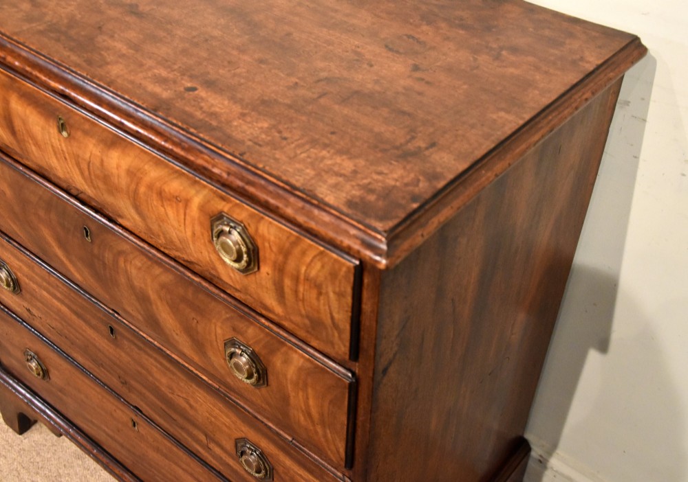 An 18th-century George III mahogany chest featuring four graduated drawers with flame mahogany veneer, octagonal brass handles, and bracket feet. View VI