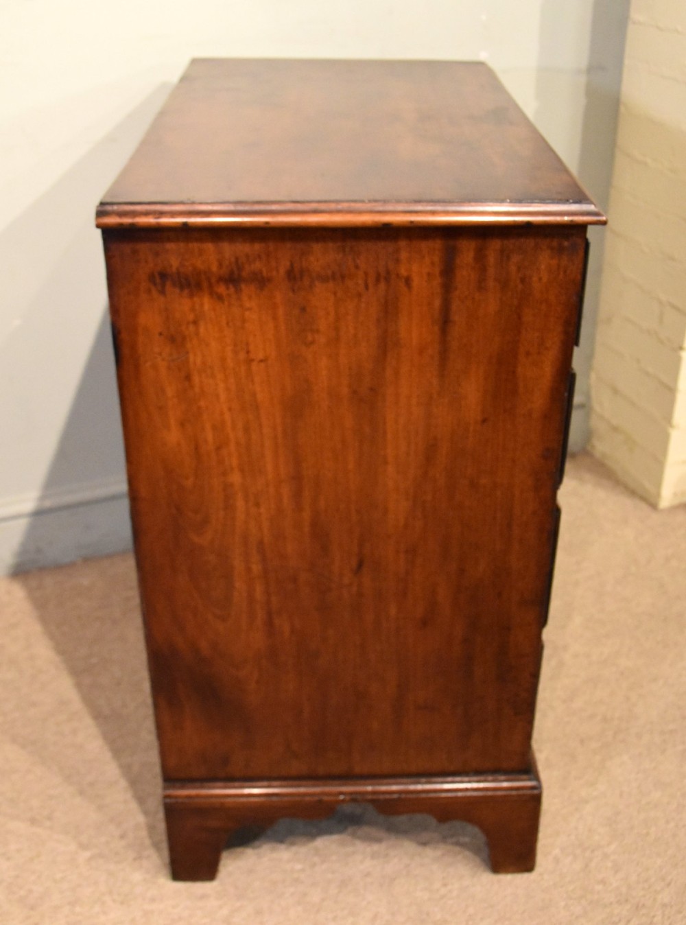 An 18th-century George III mahogany chest featuring four graduated drawers with flame mahogany veneer, octagonal brass handles, and bracket feet. View VIII