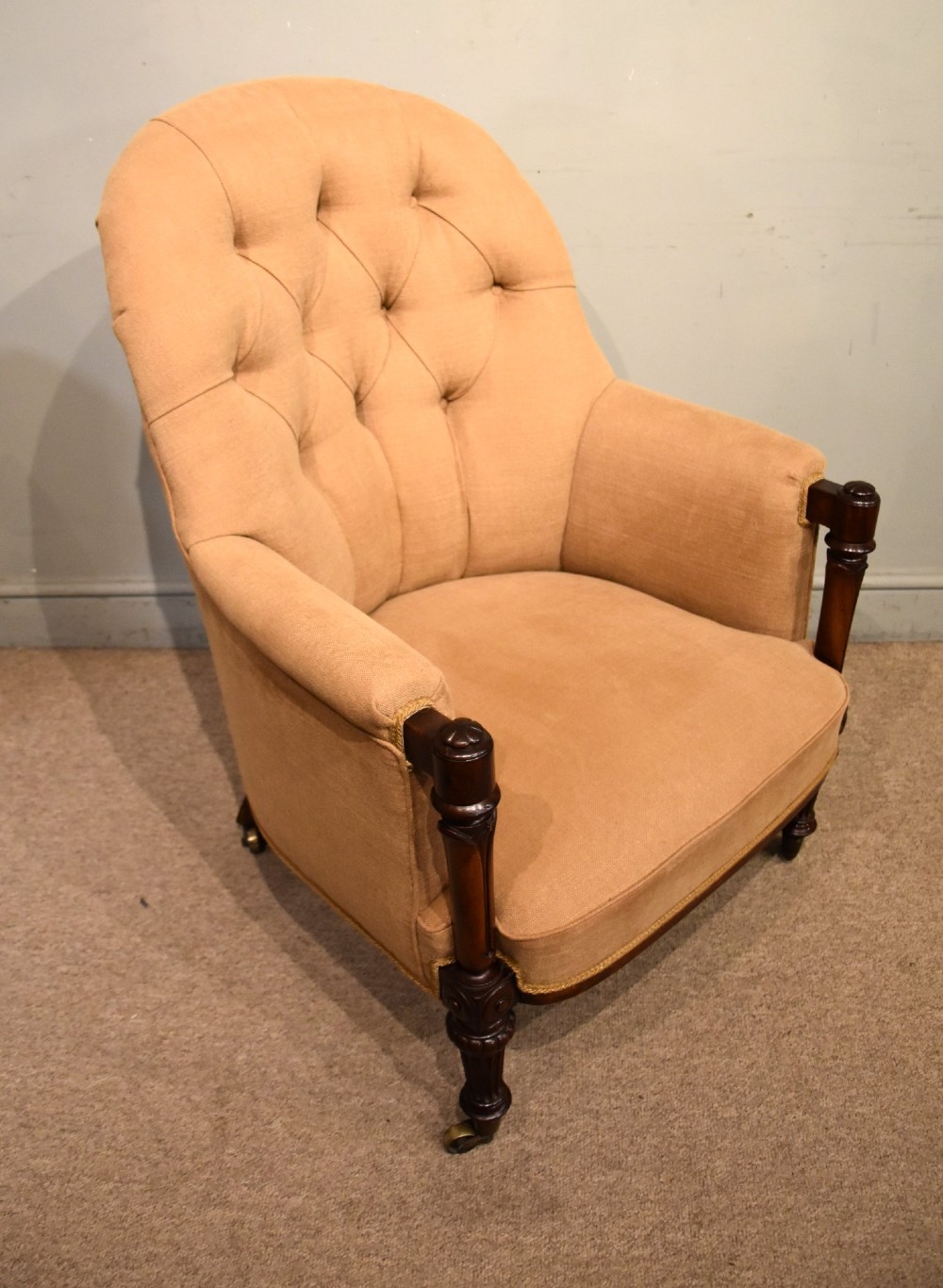 A Regency button-backed armchair upholstered in beige fabric with carved mahogany front legs on brass castors. View III