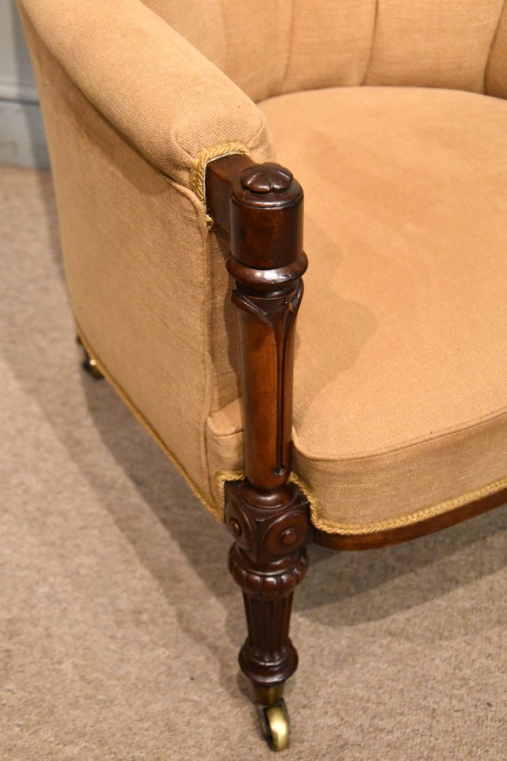 A Regency button-backed armchair upholstered in beige fabric with carved mahogany front legs on brass castors. View IV