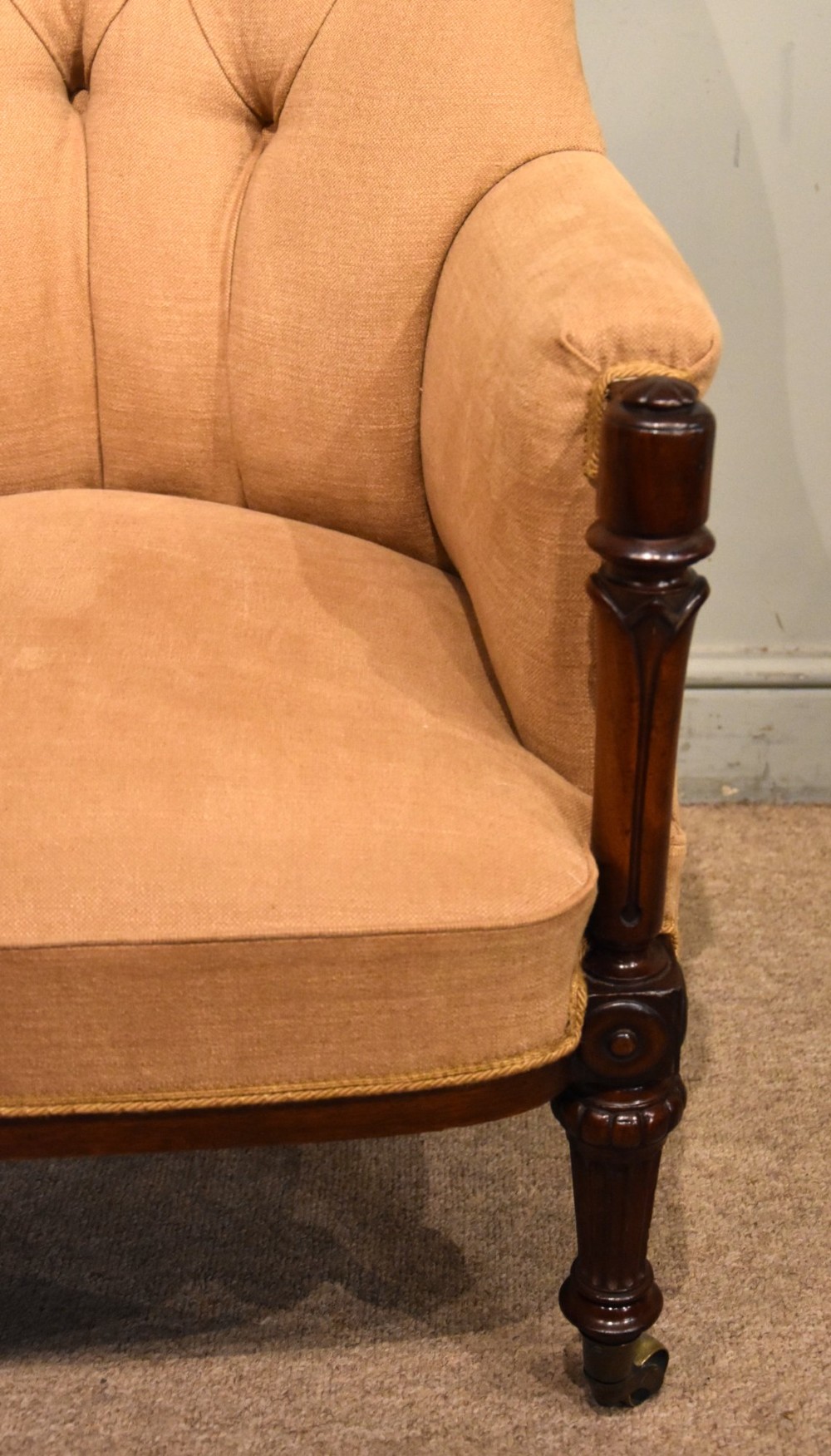 A Regency button-backed armchair upholstered in beige fabric with carved mahogany front legs on brass castors. View VI