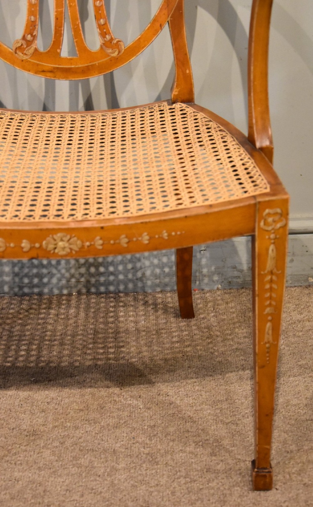 An Edwardian satinwood open armchair featuring an oval pierced backrest, hand-painted floral motifs, sweeping arms, and a woven cane seat. View II