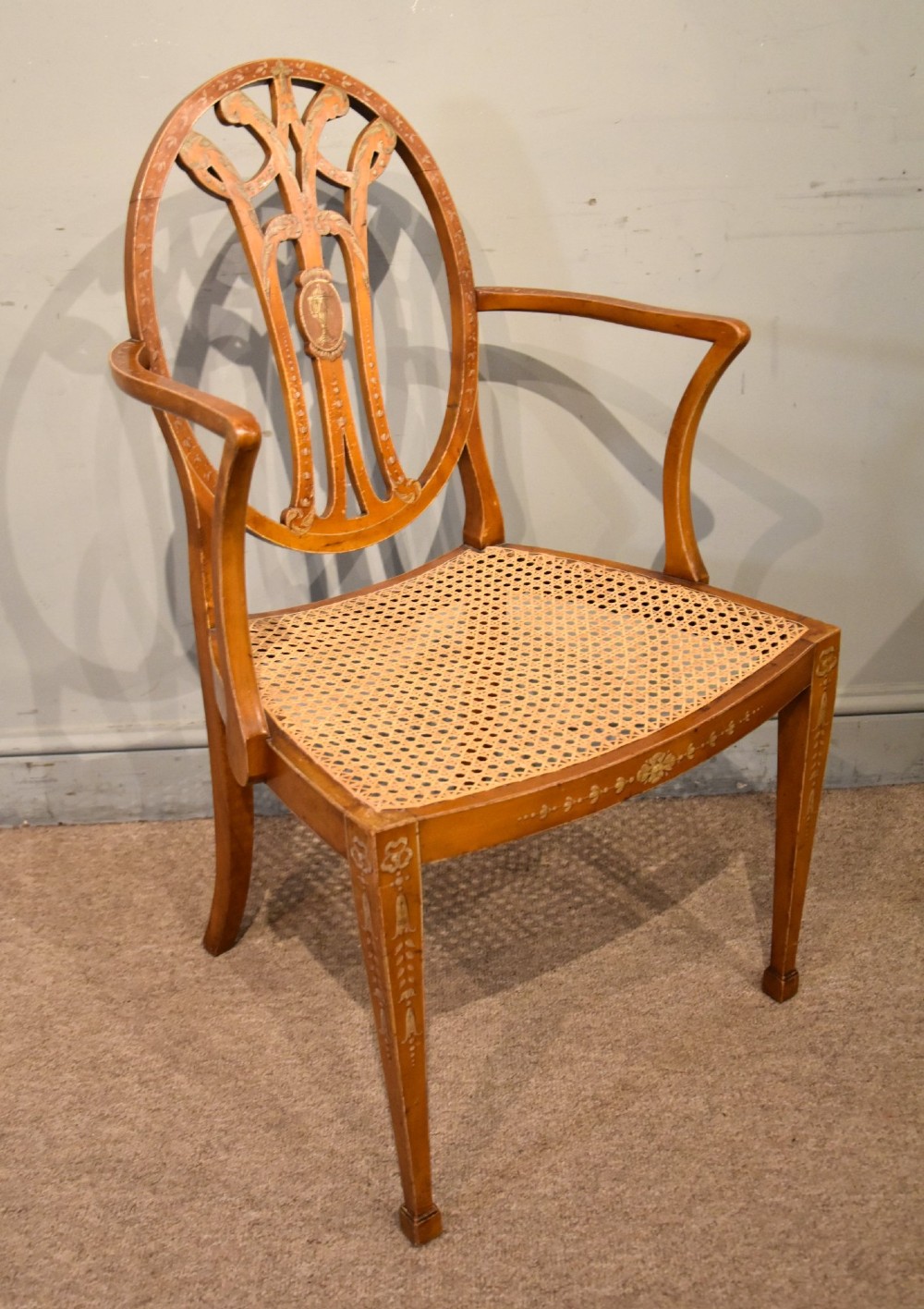 An Edwardian satinwood open armchair featuring an oval pierced backrest, hand-painted floral motifs, sweeping arms, and a woven cane seat. View III