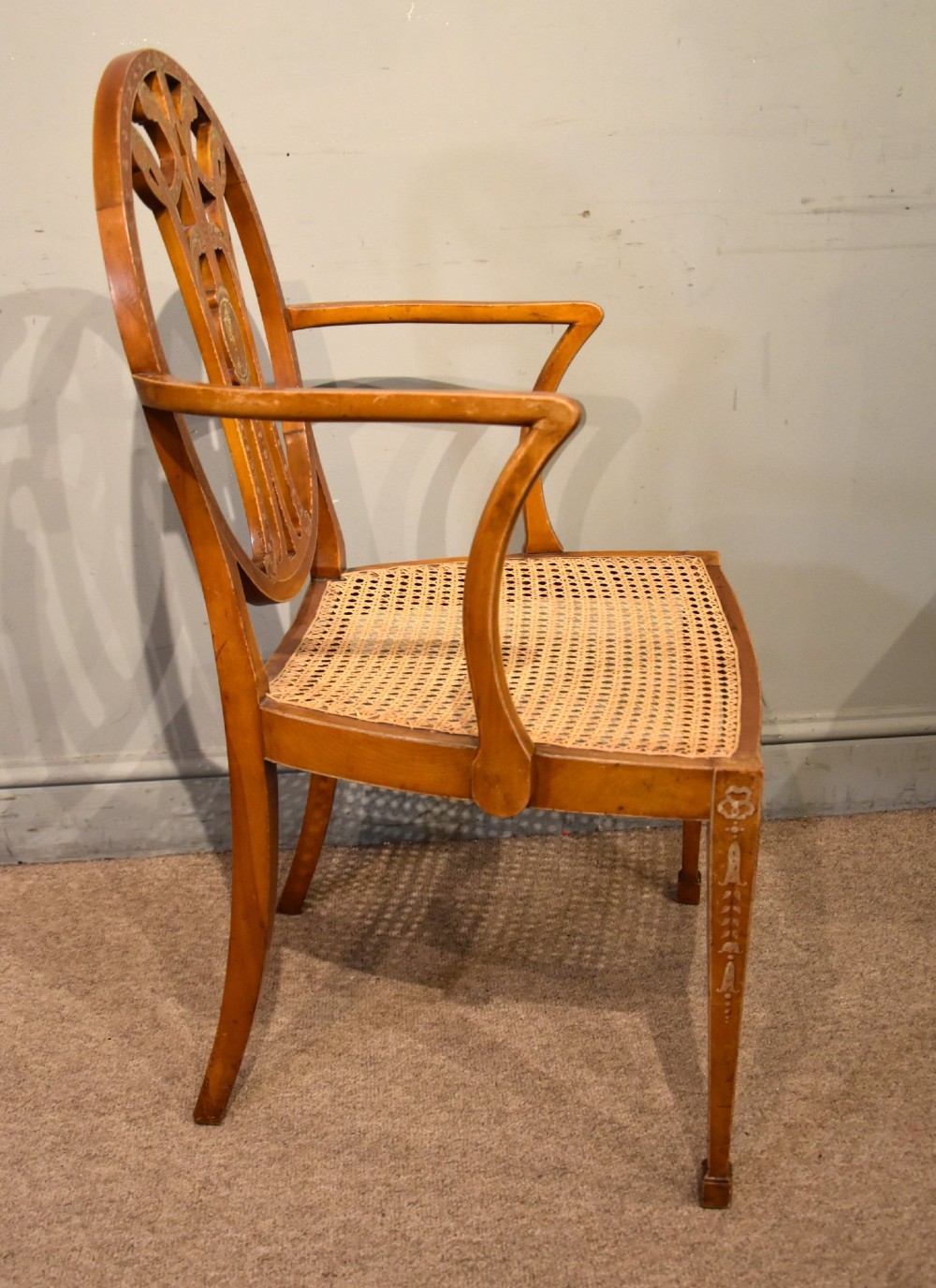 An Edwardian satinwood open armchair featuring an oval pierced backrest, hand-painted floral motifs, sweeping arms, and a woven cane seat. View IV